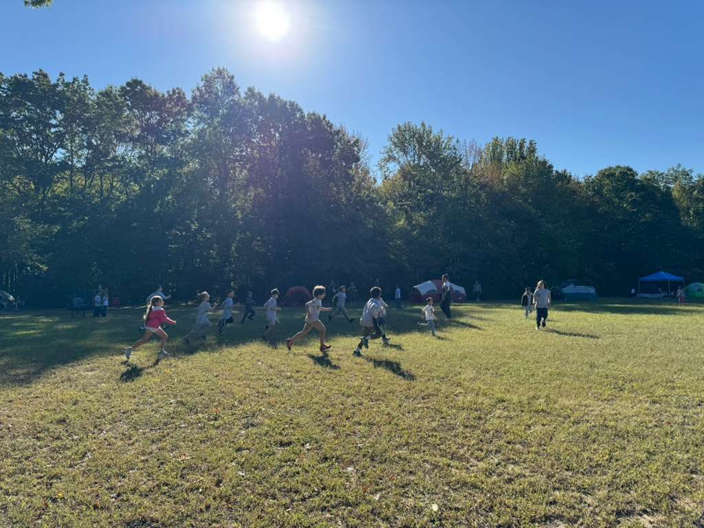 Kids running across a sunny field at camp